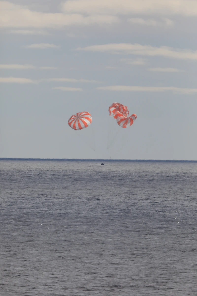Orion יורדת תחת מצנחים כתומים ולבנים מעל האוקיינוס השקט